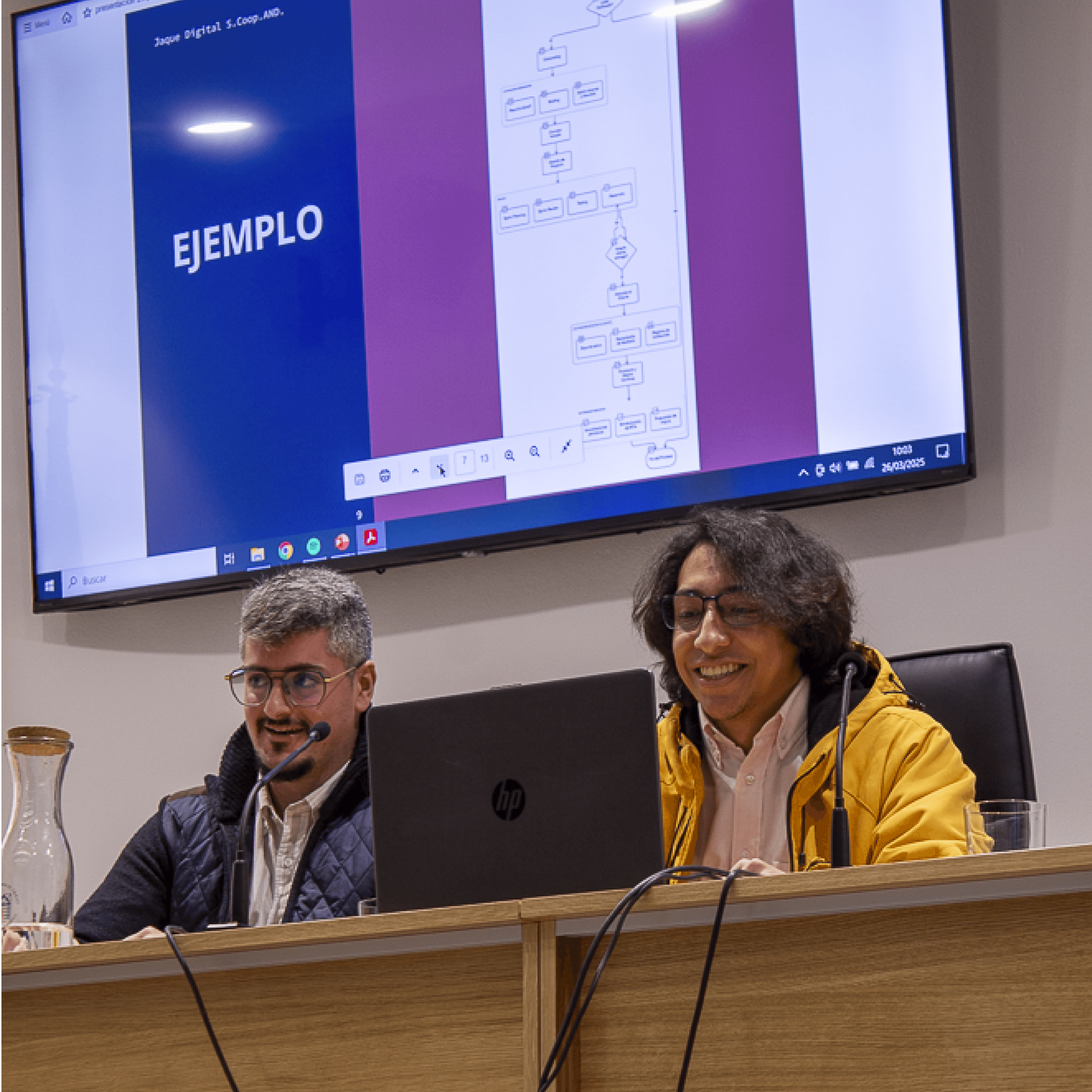 Miembros de Jaque Digital presentando un proyecto tecnológico durante una charla universitaria, con diapositivas técnicas visibles en pantalla.